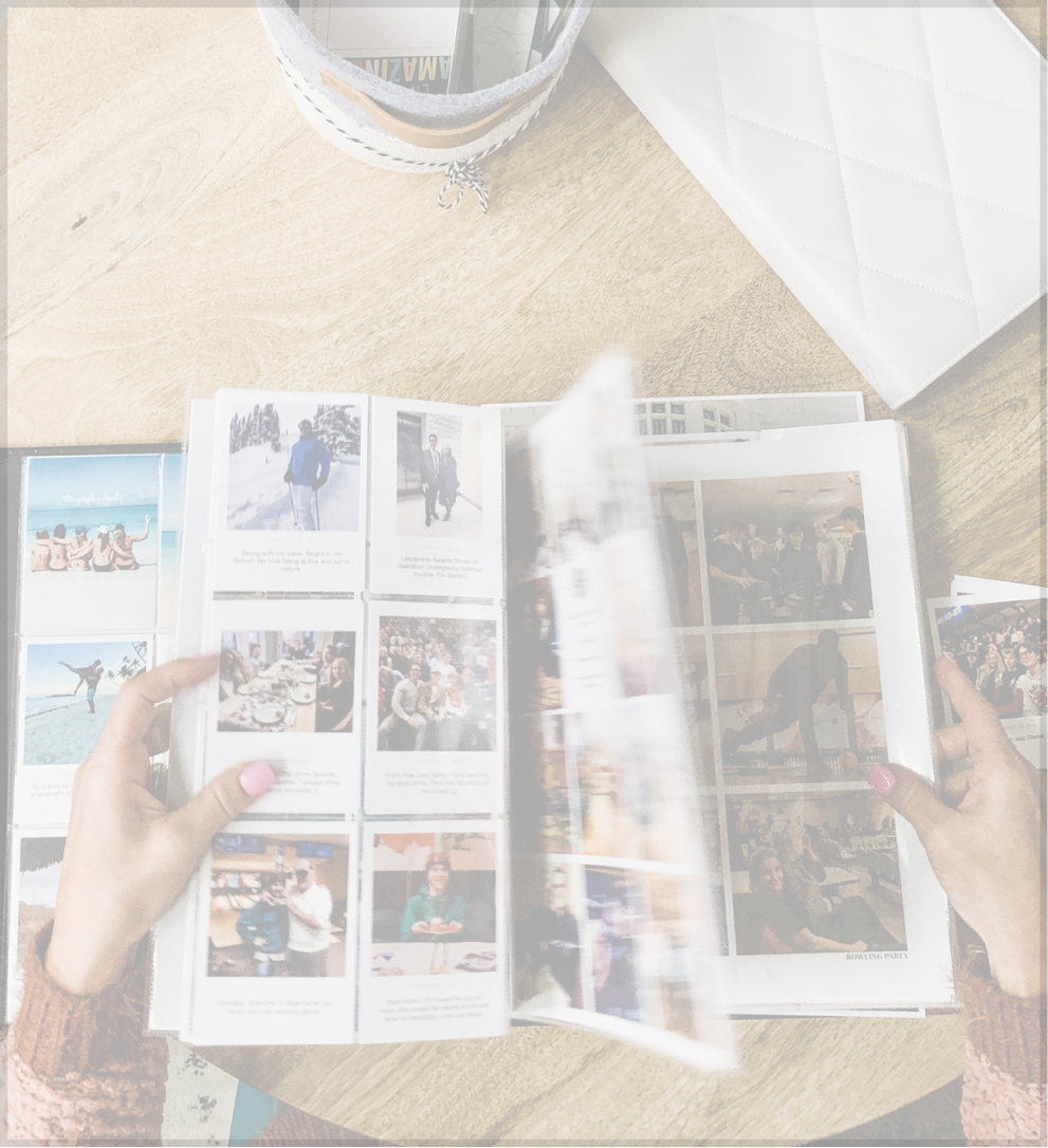 Hands browsing photo album on wooden table.