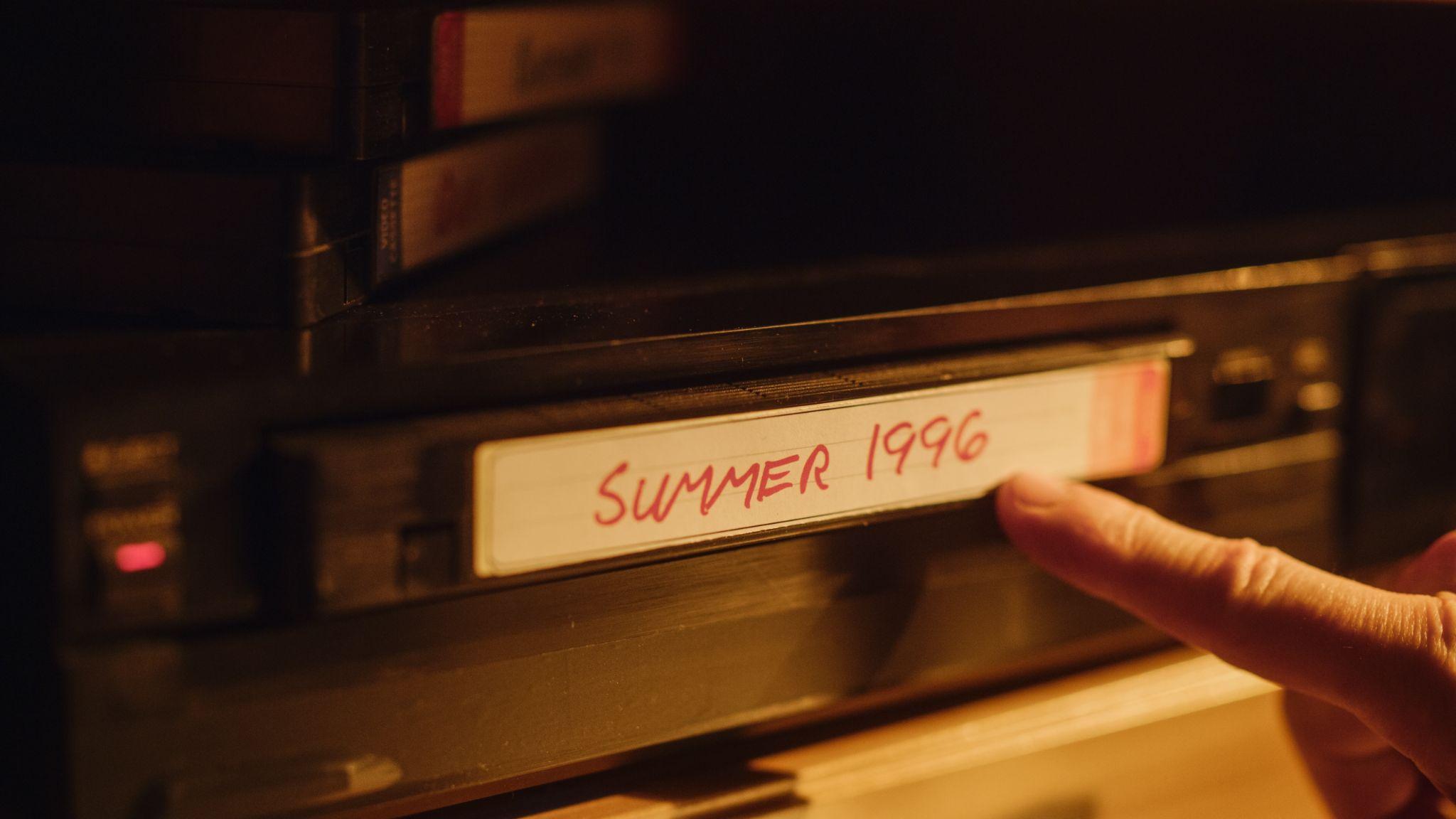 Finger touching VHS labeled 'Summer 1996'.