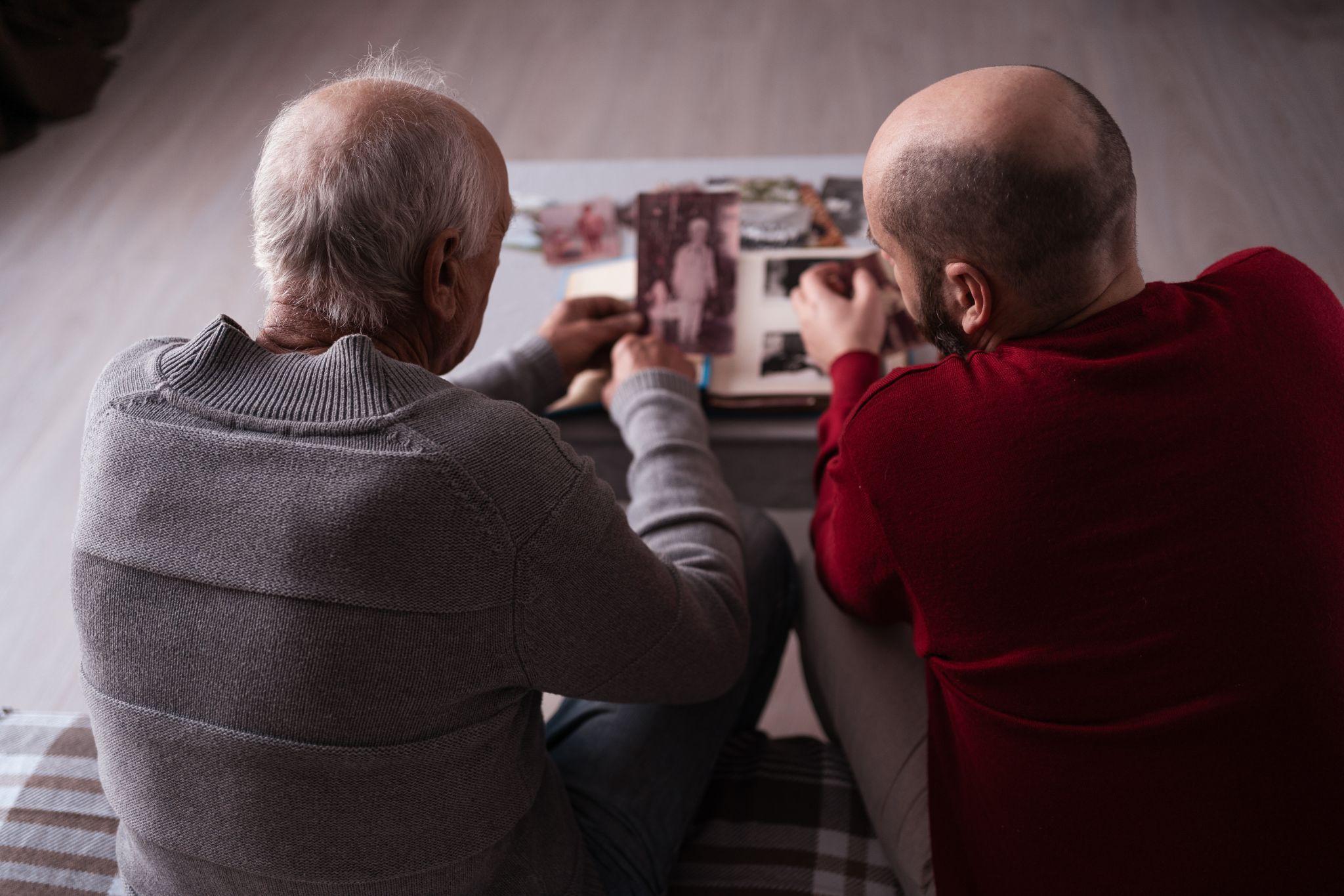 Two men looking at old photo album together.
