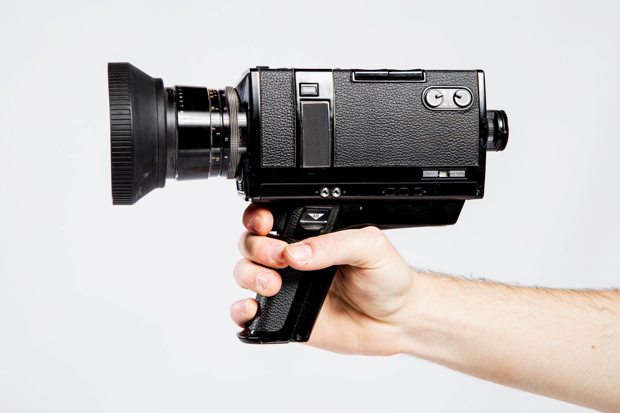 Hand holding vintage video camera against white background.